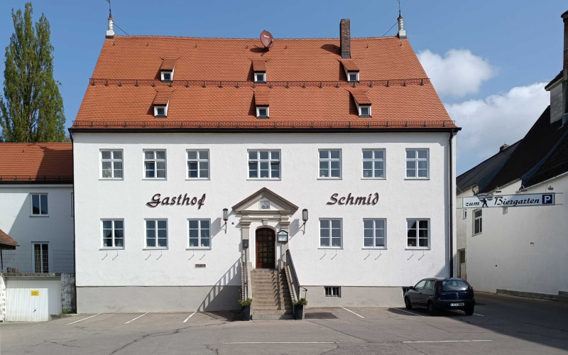 Weißes zweistöckiges Gebäude mit orangefarbenem Dach und der Aufschrift 