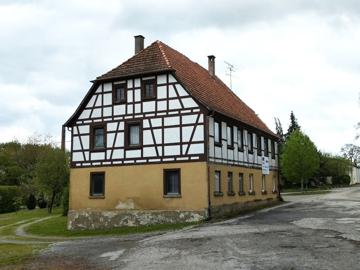 Fachwerkhaus mit gelbem Sockel und Ziegelsteingiebel.