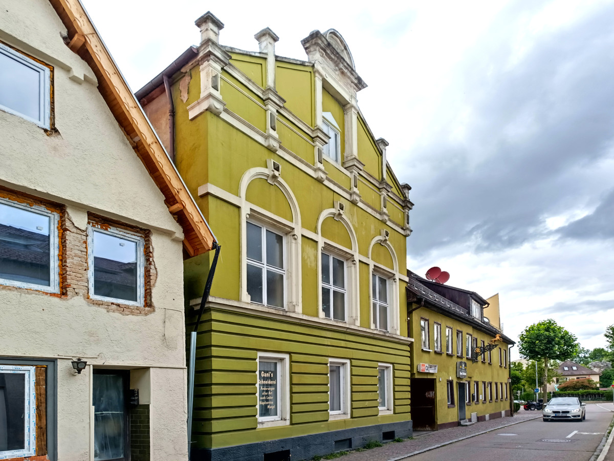 Stra&szlig;enansicht mit historischen Geb&auml;uden in Gelb- und Wei&szlig;t&ouml;nen, charakteristisch f&uuml;r eine kleine Stadt mit klassizistischer Architektur und ornamentalen Fassadengestaltungen.